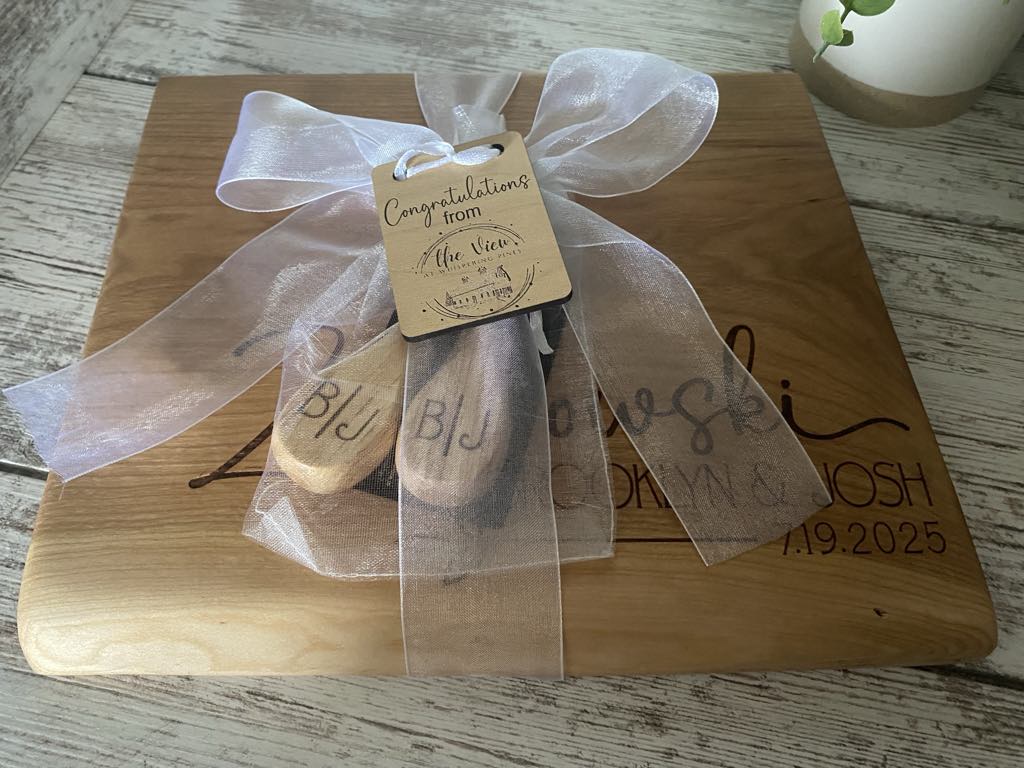 Live edge cherry serving board wrapped with a white bow and gift tag, handcrafted as a wedding or housewarming gift