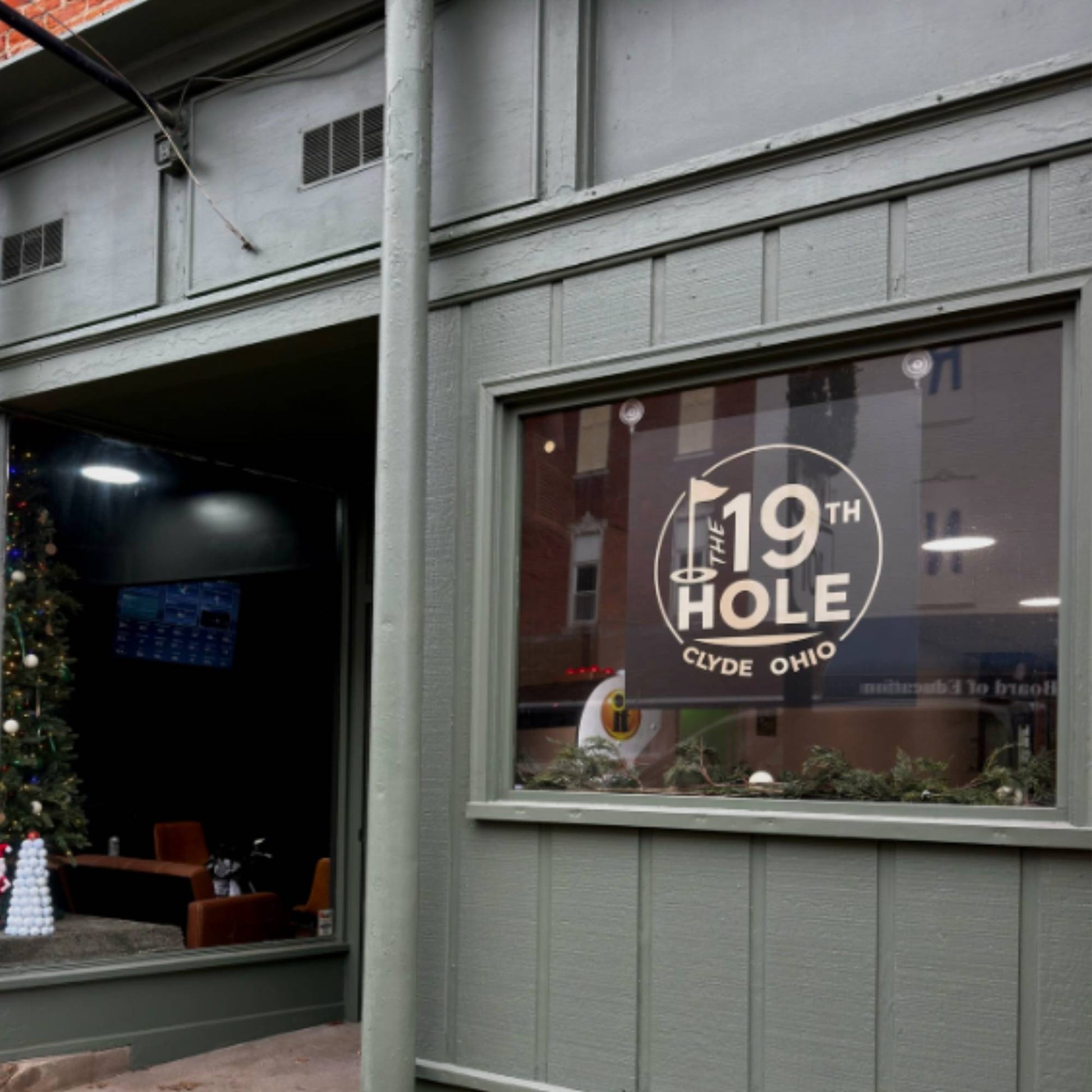 black metal and white acrylic layered business sign crafted by Quirky Pirate hung in front store window of The 19th Hole