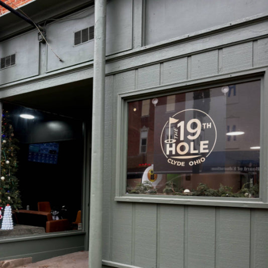 black metal and white acrylic layered business sign crafted by Quirky Pirate hung in front store window of The 19th Hole