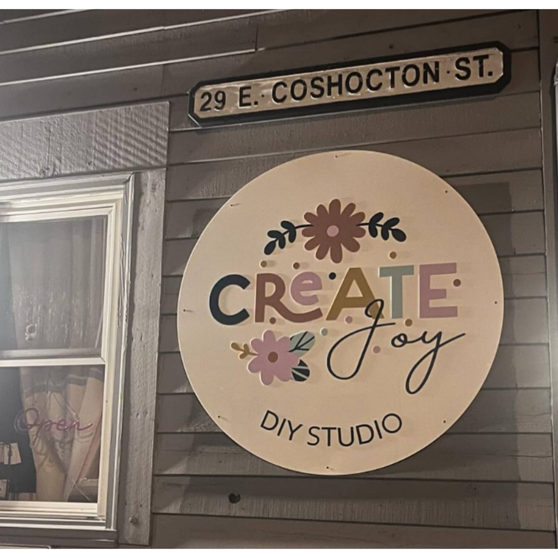 round layered acrylic business sign hung on outside of store.