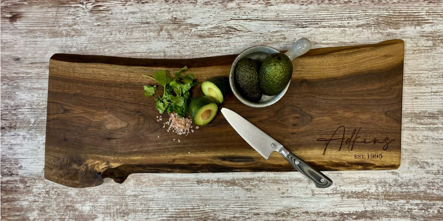walnut live edge serving board customized with name sitting on counter with knife and avocado
