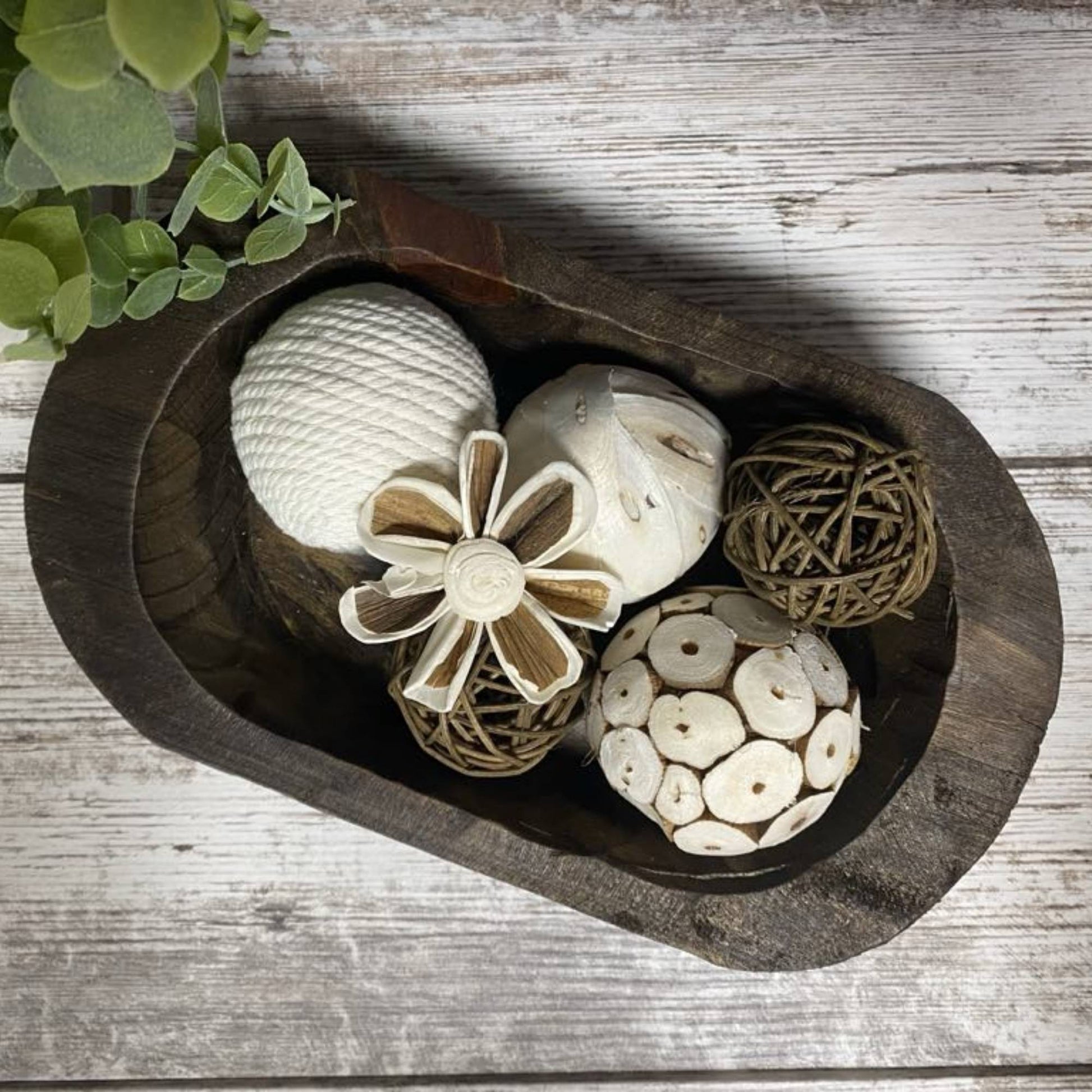 top view of a hand carved wood bowl with decor pieces in it.