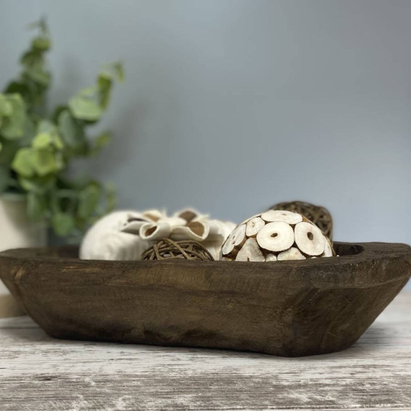 hand carved wood bowl with decorative items in it on a shelf