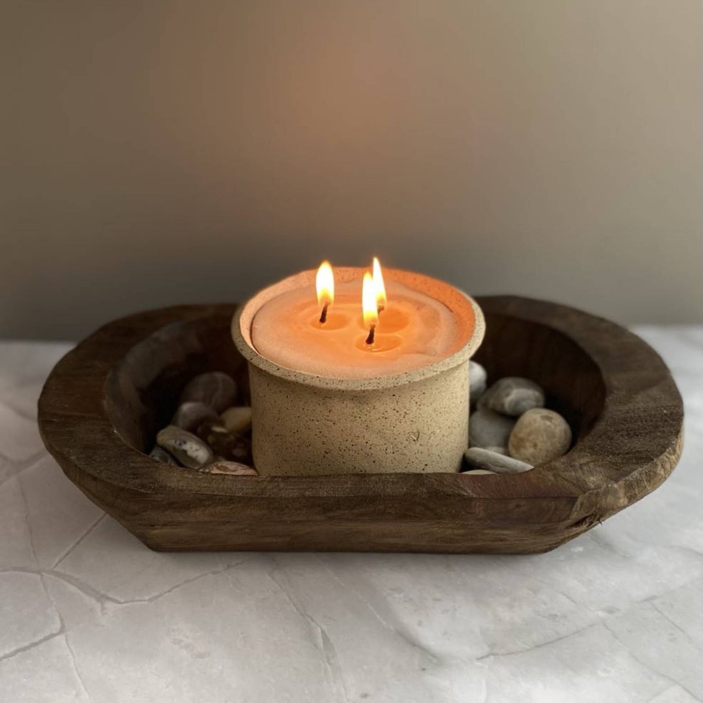 hand carved wood bowl with a lit candle and small stones in it 