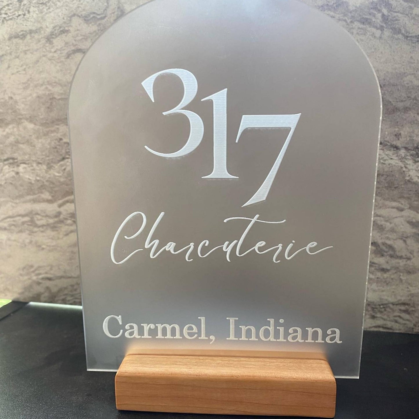frosted acrylic business name sign with hardwood base sitting on counter
