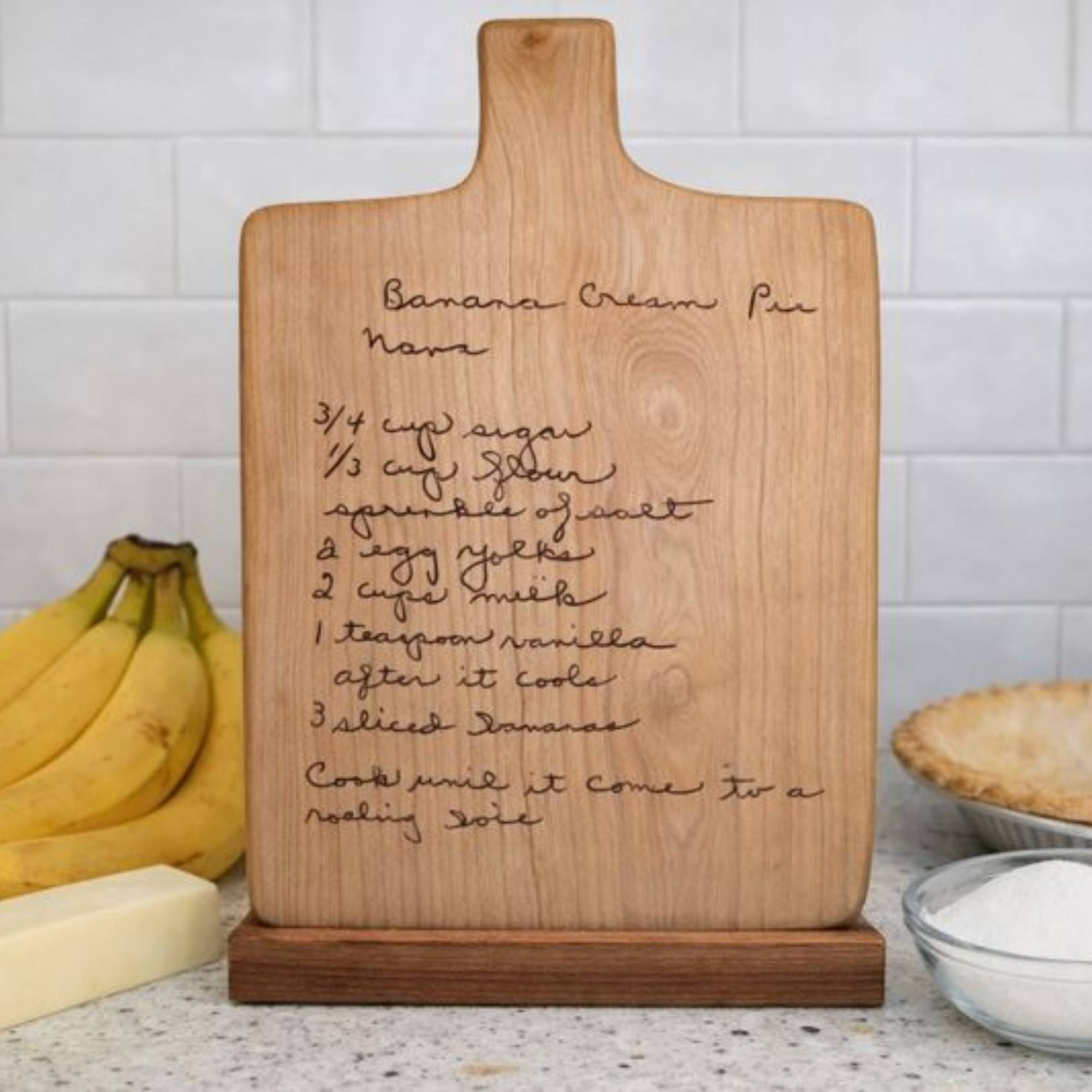 custom engraved recipe board on a wood stand on the kitchen counter