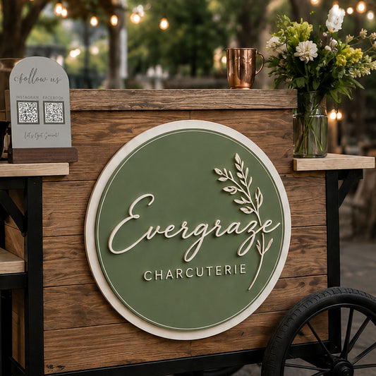 Round layered Evergraze logo sign mounted on a rustic charcuterie cart