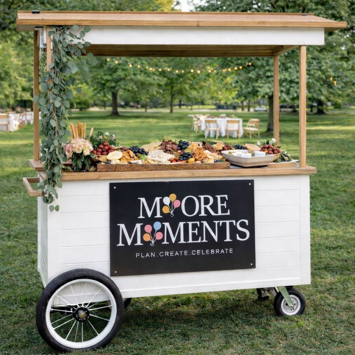 Moore Moments Charcuterie logo sign mounted on a white mobile grazing cart