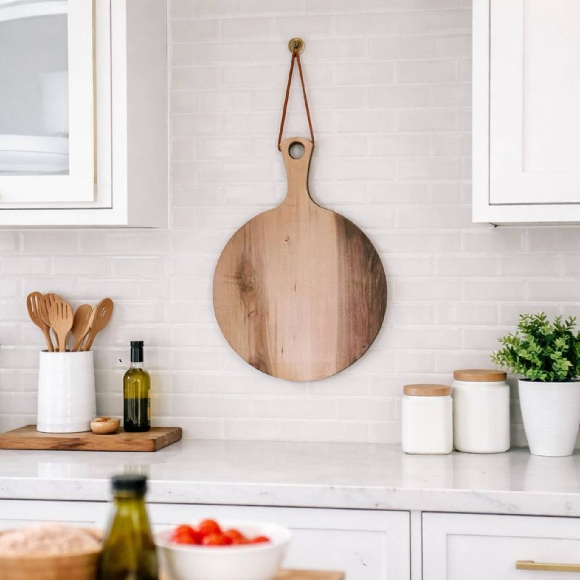 round wood serving board hanging on kitchen wall