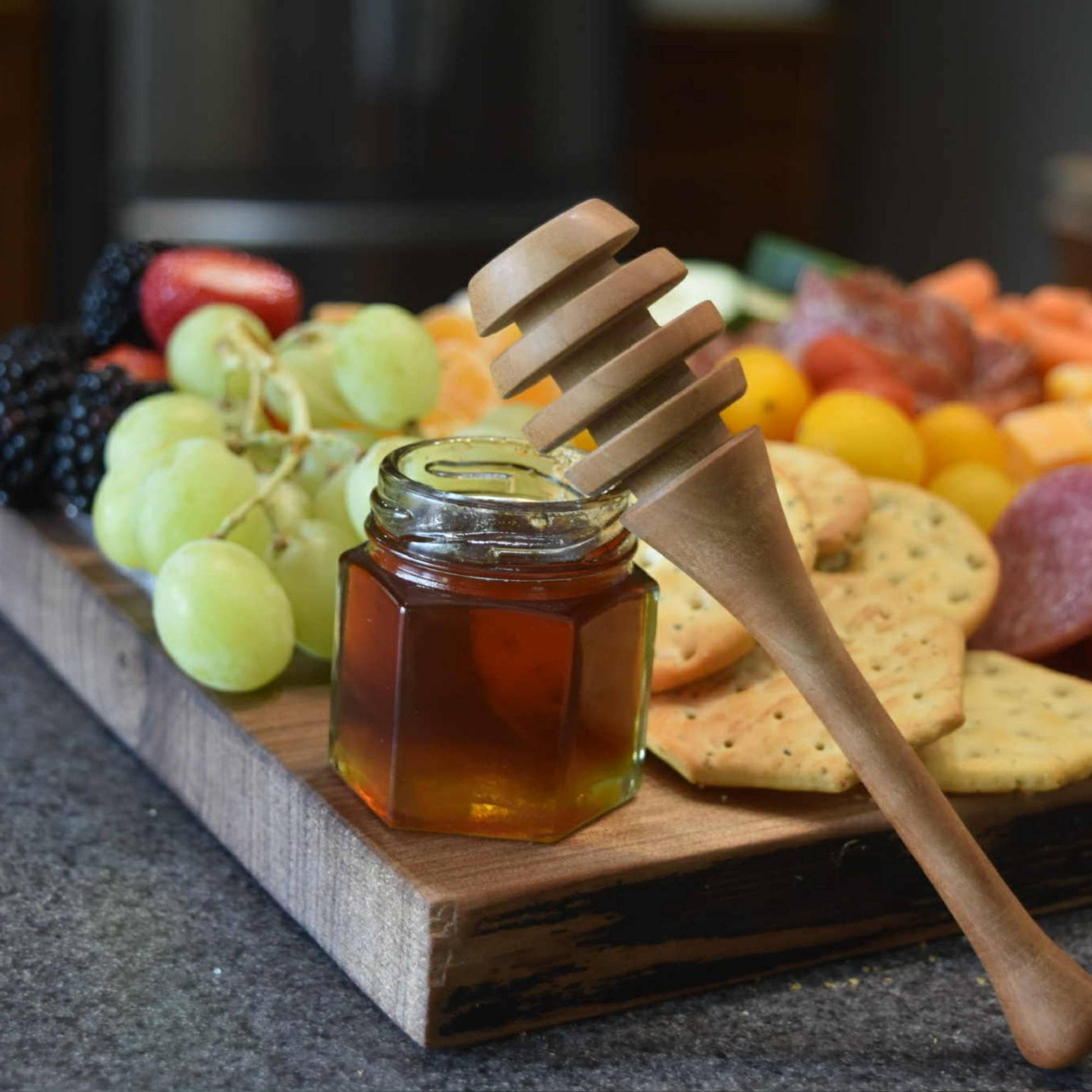 close up walnut live edge serving board with honey and honey dipper