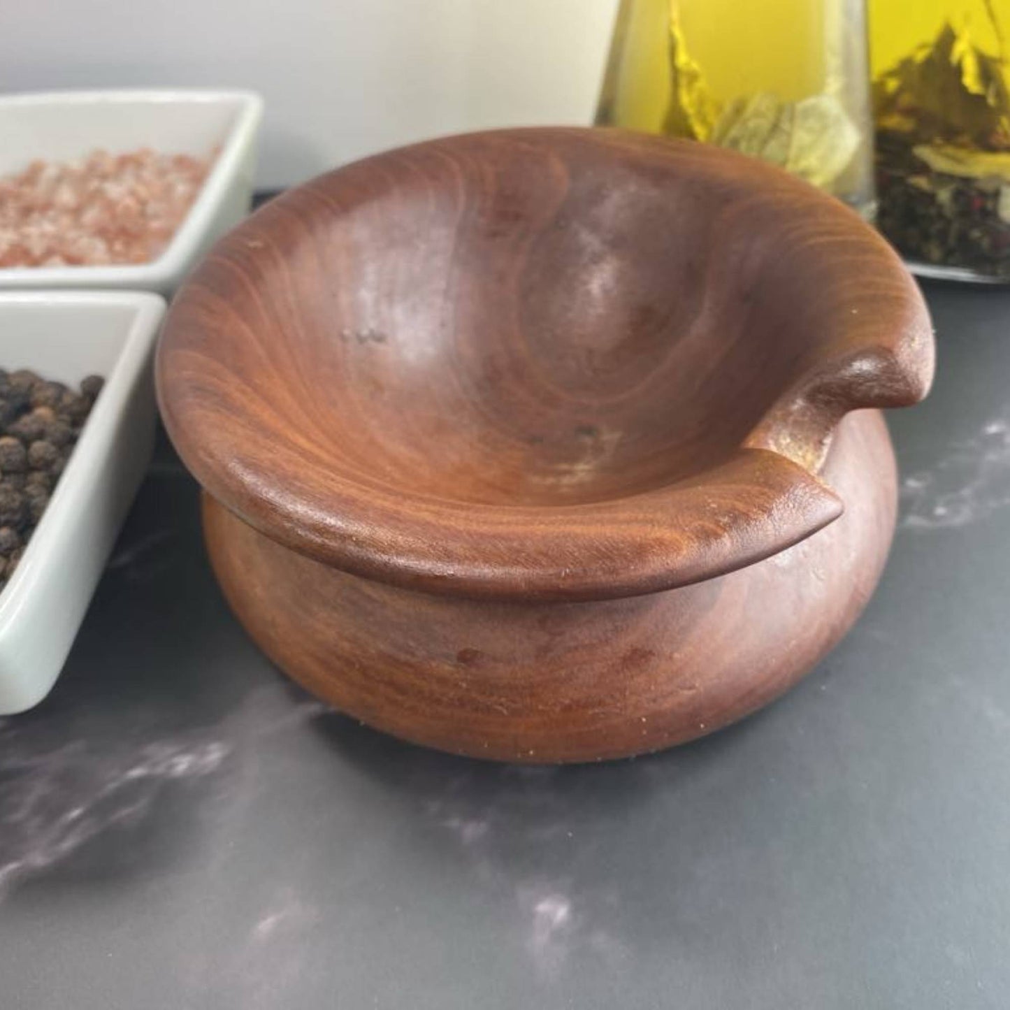 hand turned wood kitchen spoon rest sitting on kitchen island with oil and salt